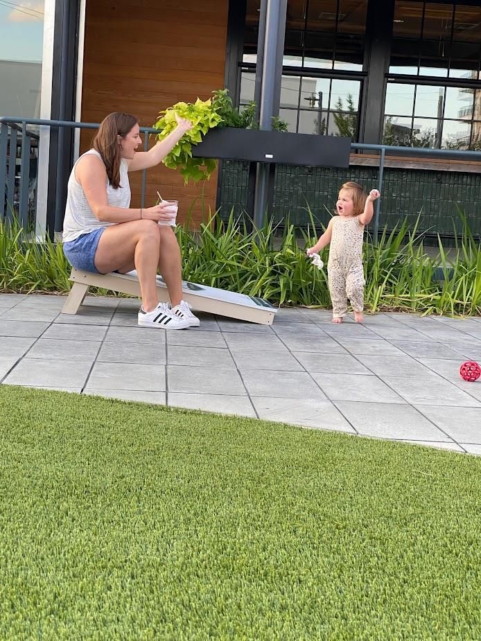 sitting woman and standing toddler tossing ball outdoors